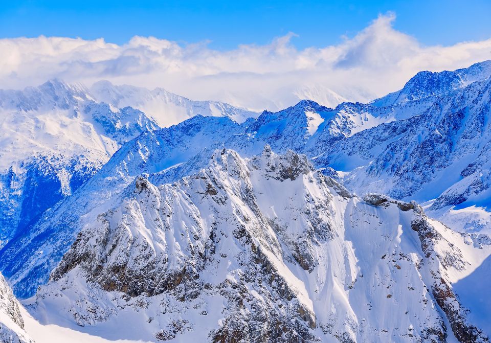 Blue skies and thick clouds above the snowy mountains in Switzerland