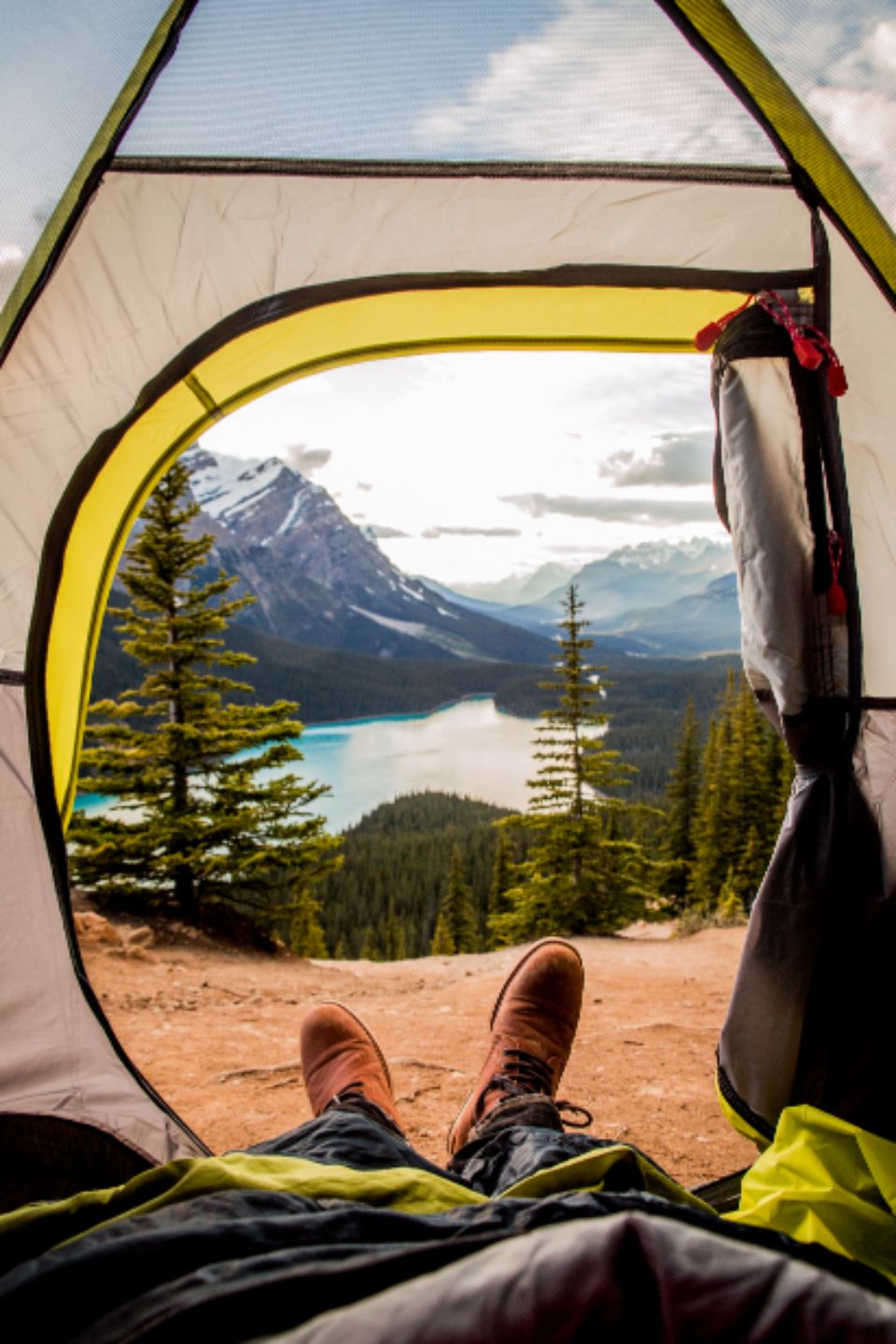 two feet stick out a tent with the view of a mountain and trees in the background