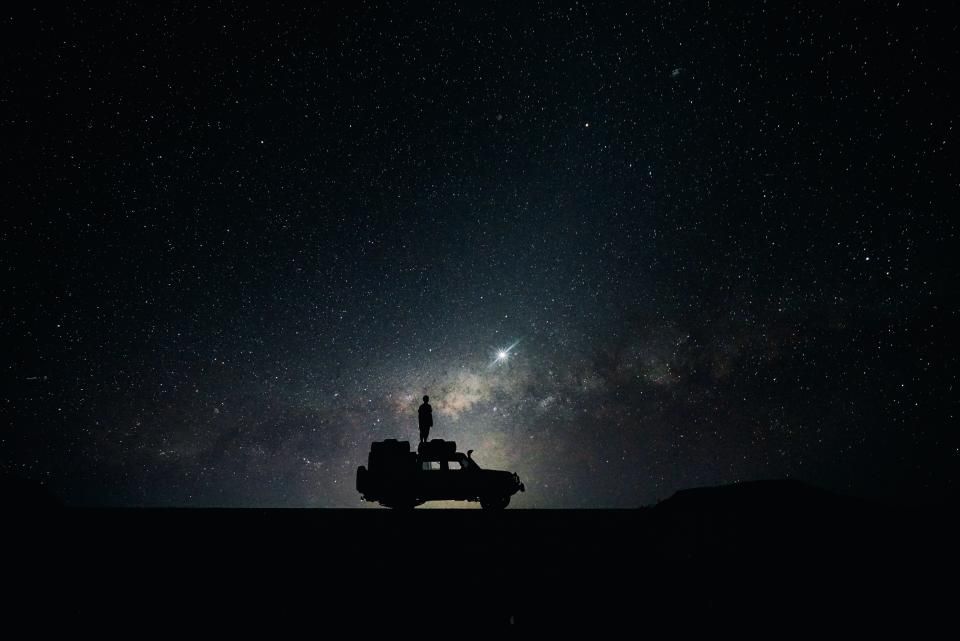 silhouette of a person and vehicle set against the starry night sky