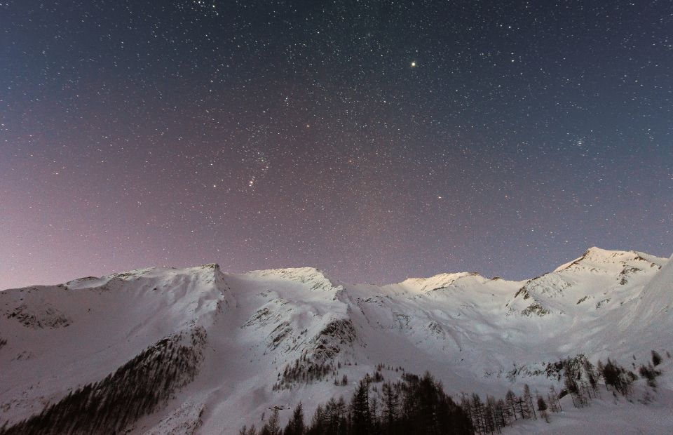 snowy mountain range under a night sky full of stars