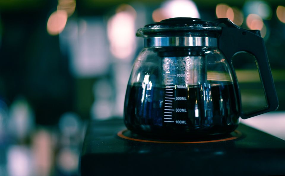 a coffee maker half-full of coffee with bokeh lights in the background