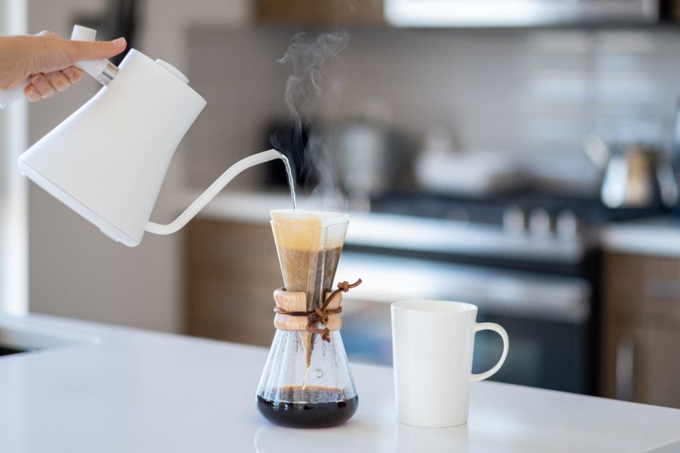 a person pours hot water into a glass coffee funnel with filter