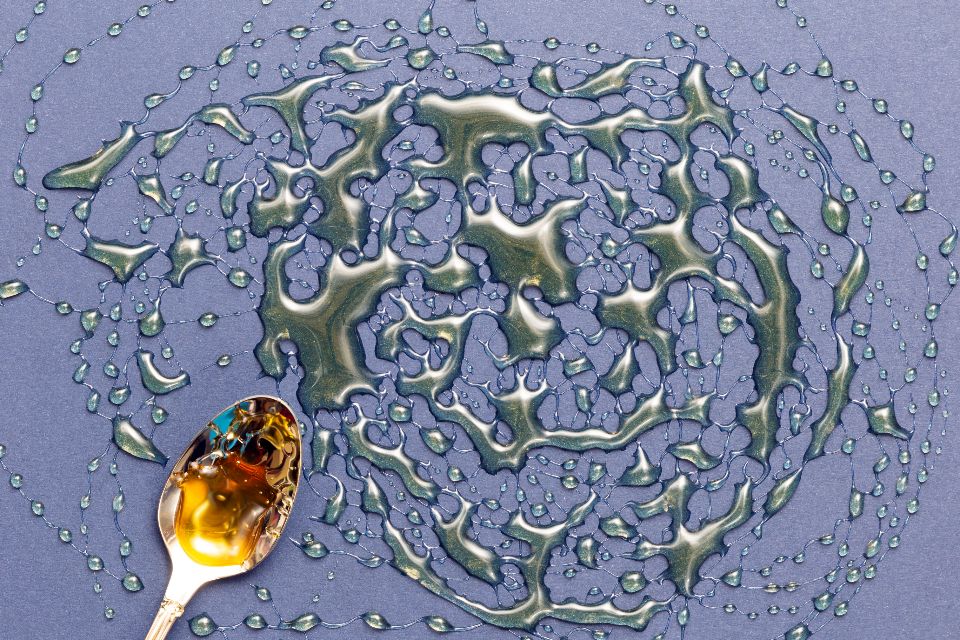 a silver spoon sits on a blue surface drizzled with honey