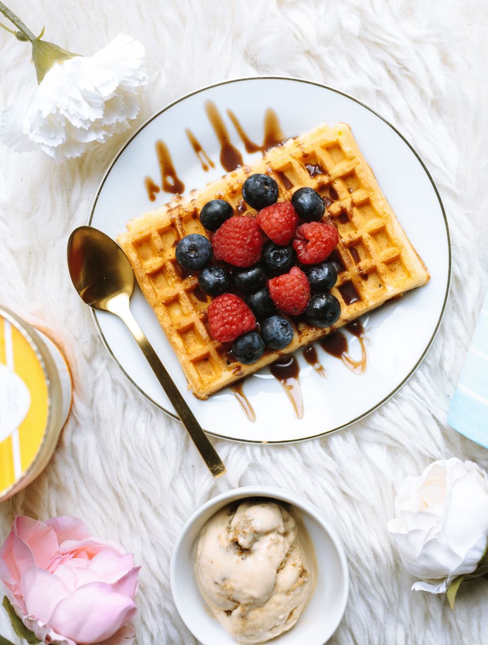 overview shot of waffles with berries, icecream and flowers