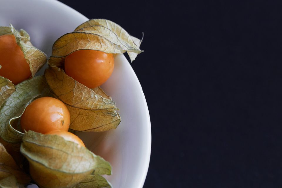 gooseberries sit in a white ceramic dish on a black surface 