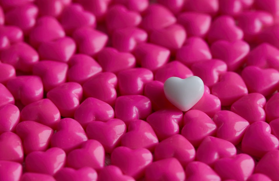 a single white heart sits on a pile of 3D pink hearts
