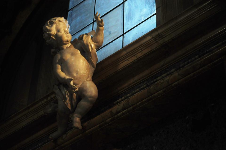 a statue of cupid on the side of a building, outside of a window