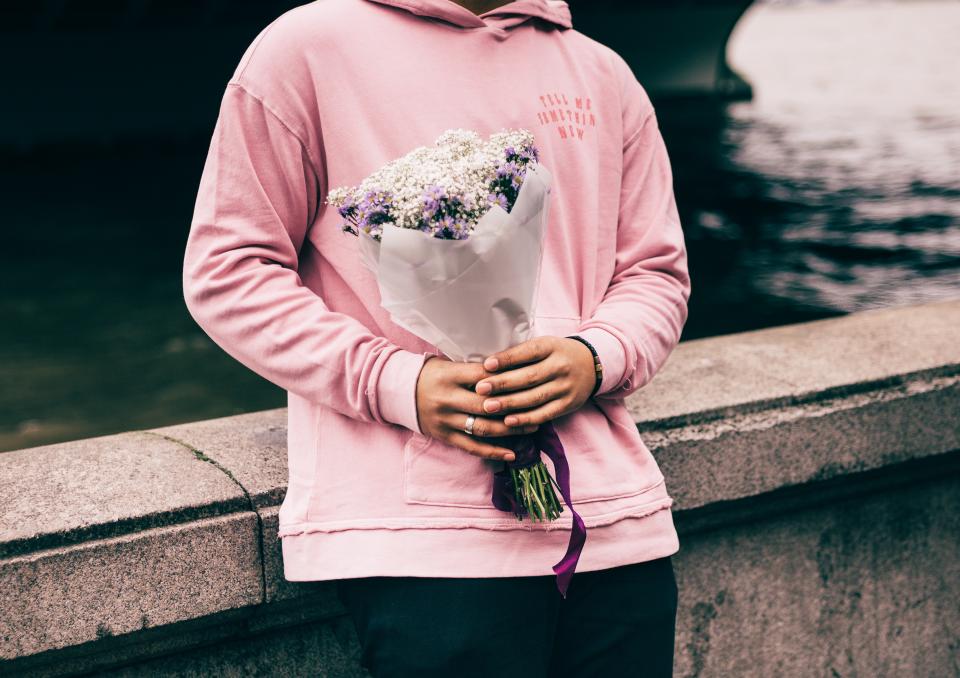 a person in a pink hoodie holds a bouquet of flowers 