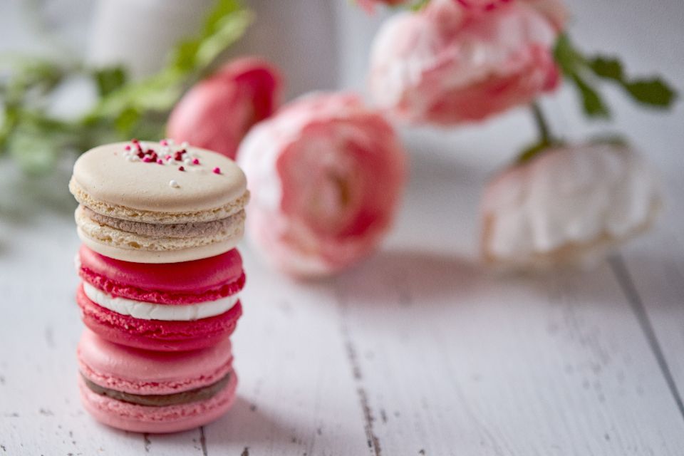 a stack of three macarons with flowers in the distance on a rustic white surface