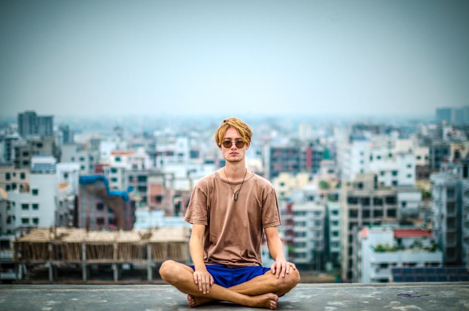 a man sits cross-legged on a rooftop to practice meditation