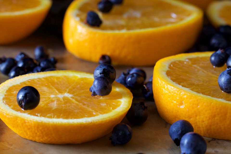 slices of oranges and blueberries sit on a surface