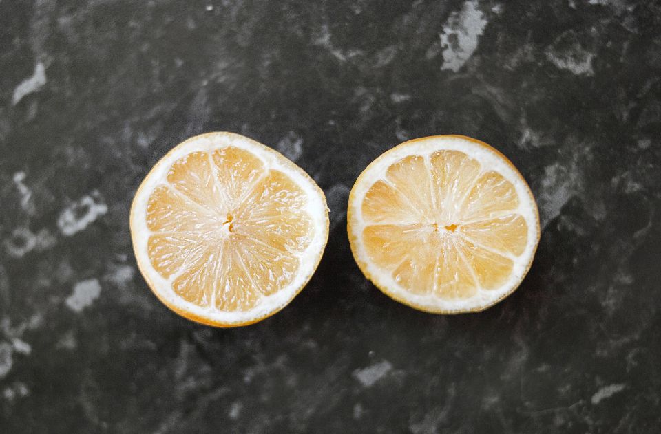 two lemon halves sit on a marble counter