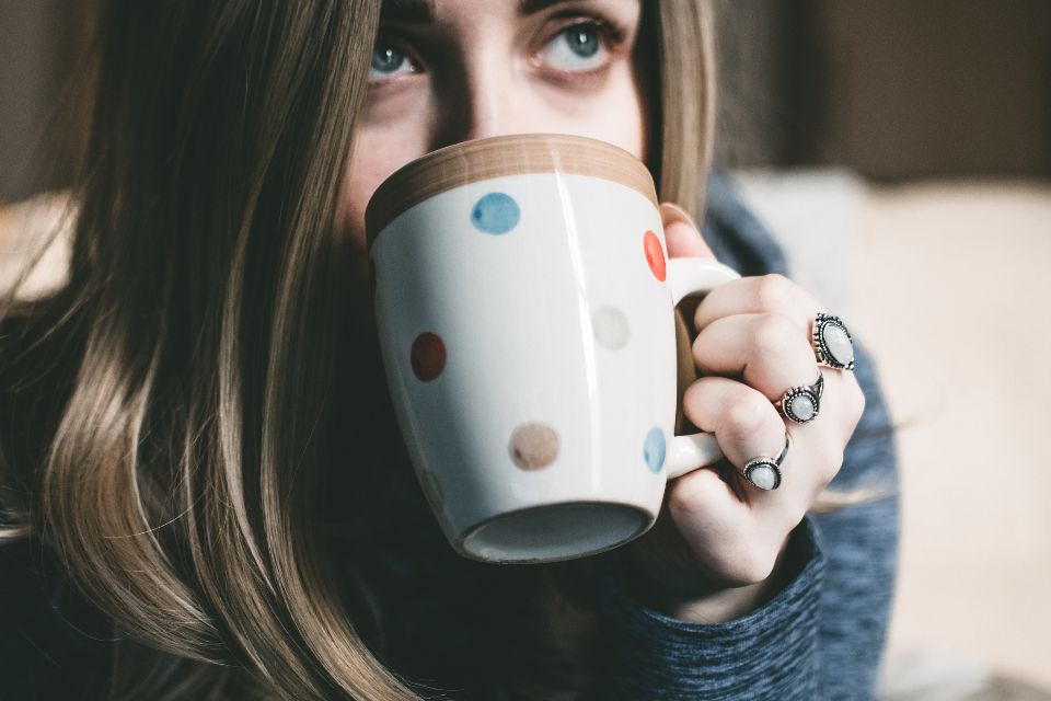 a woman sips from a mug with polka dots