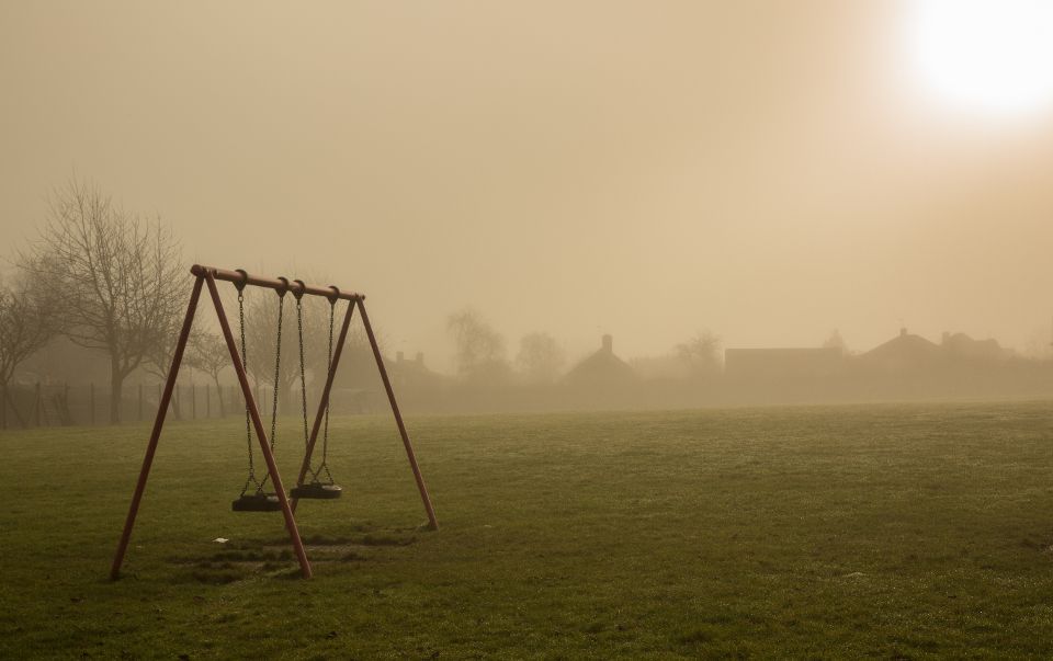 an empty swingset is shown during sunrise.