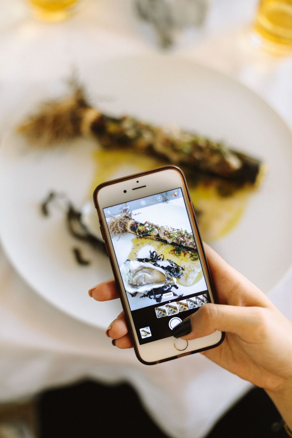 photograph of someone taking a mobile phone image of a plate of seafood