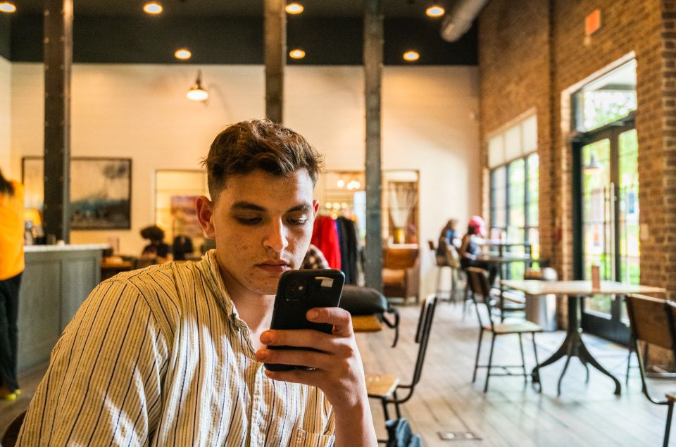 man editing his smartphone photography while sitting at a cafe