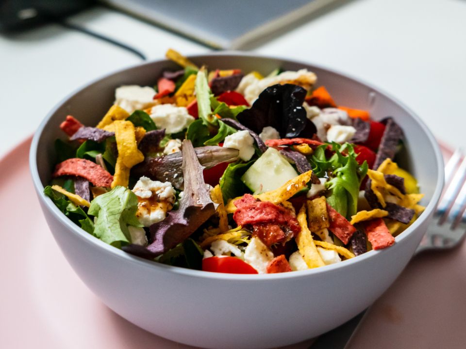 brightly lit food photograph of a colorful southwest salad in a white ceramic bowl