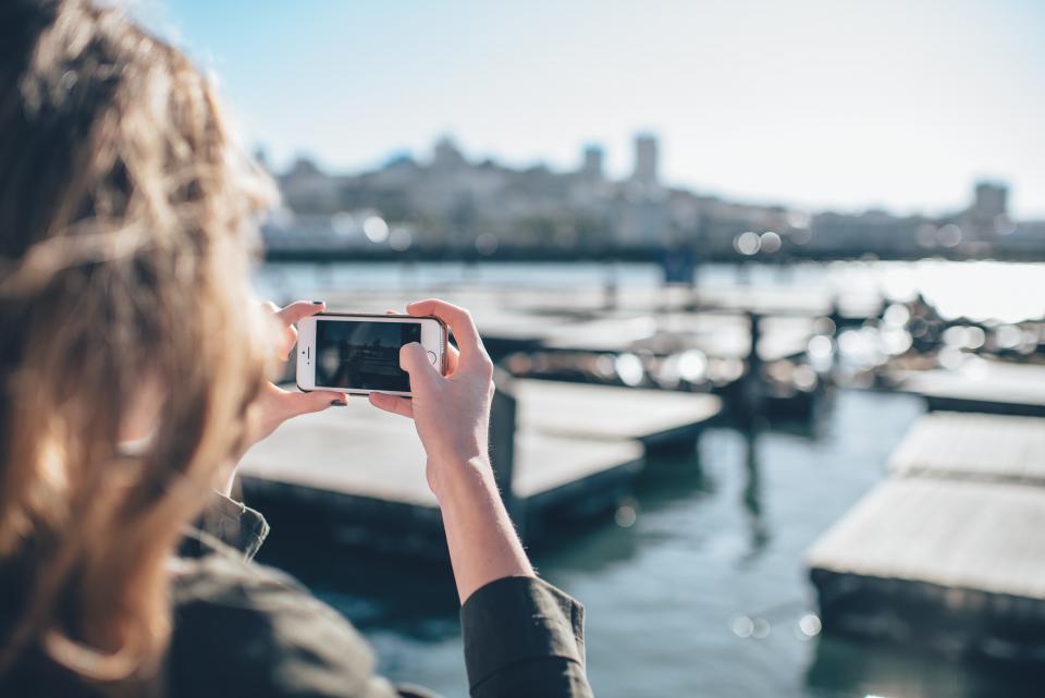 woman using a smartphone to take a photograph of a harbor